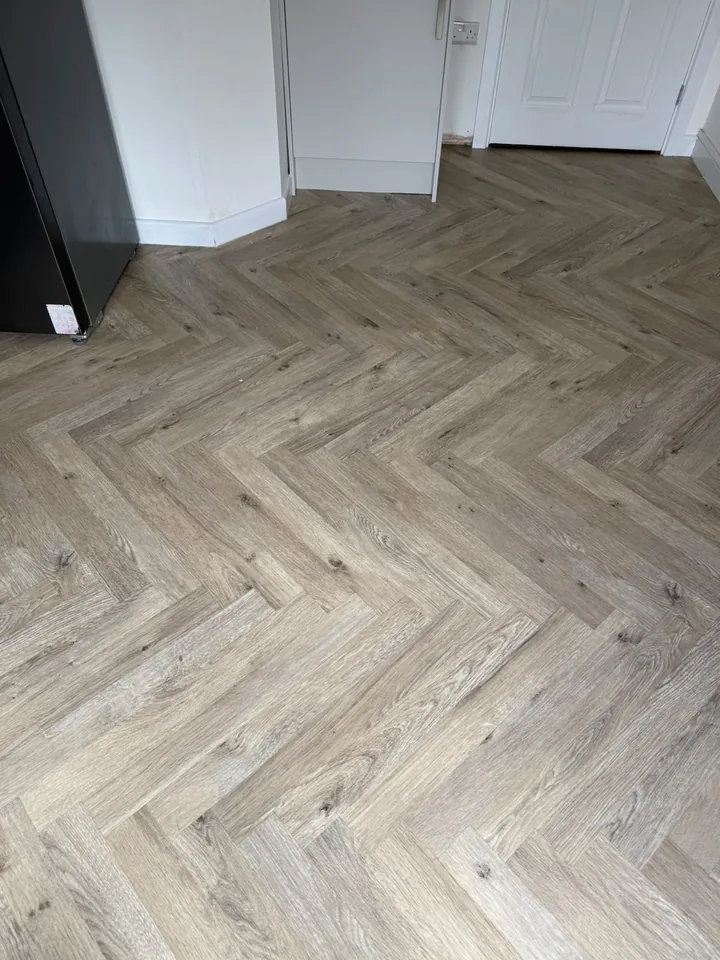 Light wood-effect herringbone vinyl fitted around white kitchen units